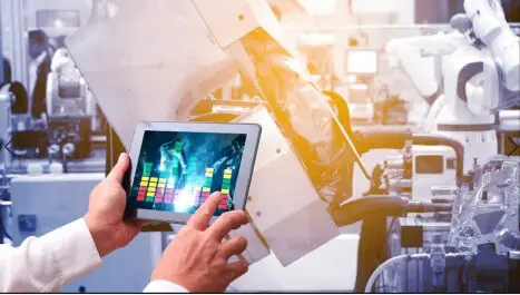 A man is using a tablet in a factory.