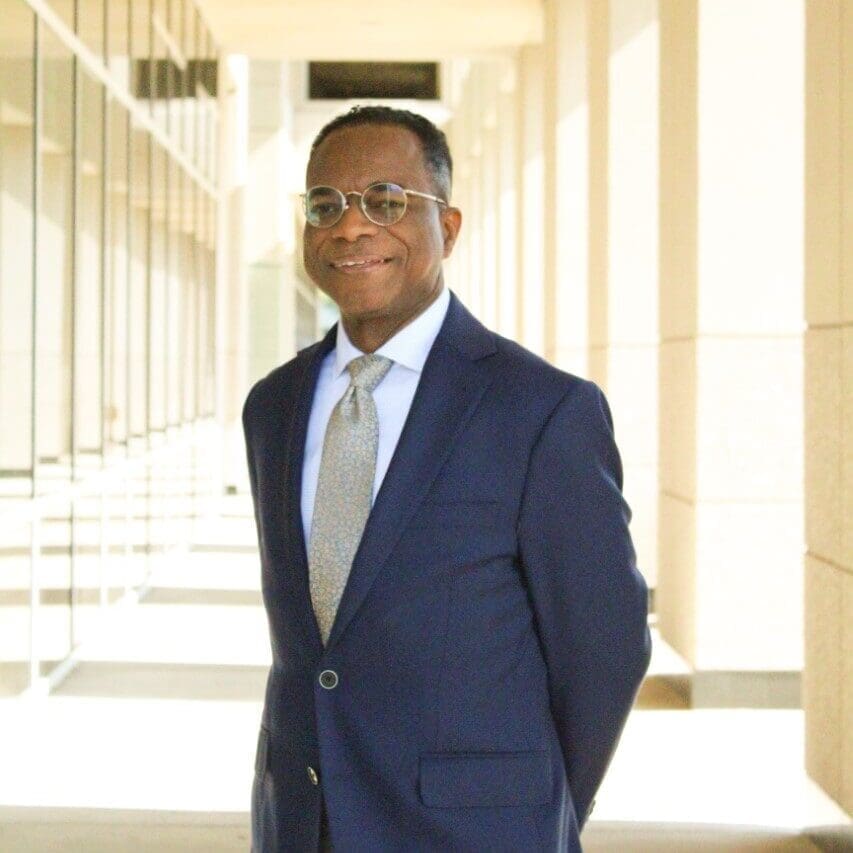 Man in suit standing in bright corridor.